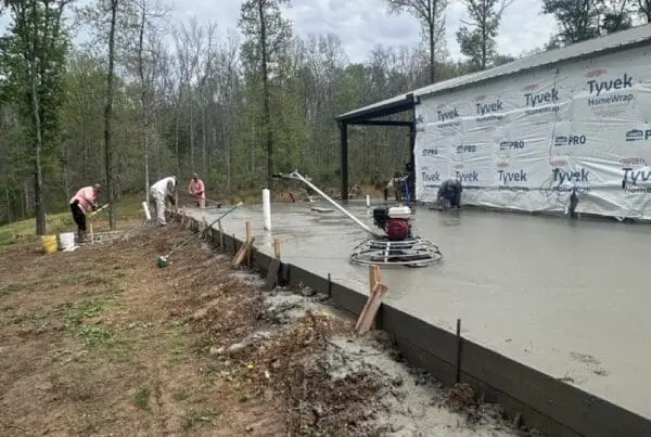 Construction crew smoothing a concrete slab in Middle Tennessee for an expanded master suite and home office.