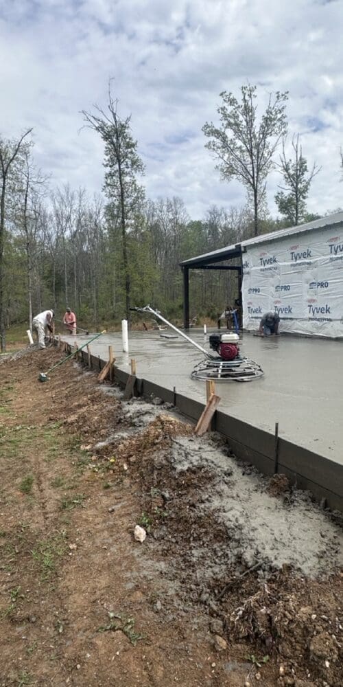 Construction crew smoothing a concrete slab in Middle Tennessee for an expanded master suite and home office.