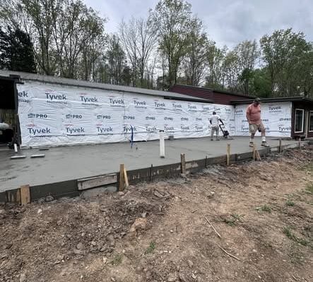 Construction crew smoothing a concrete slab in Middle Tennessee for an expanded master suite and home office.